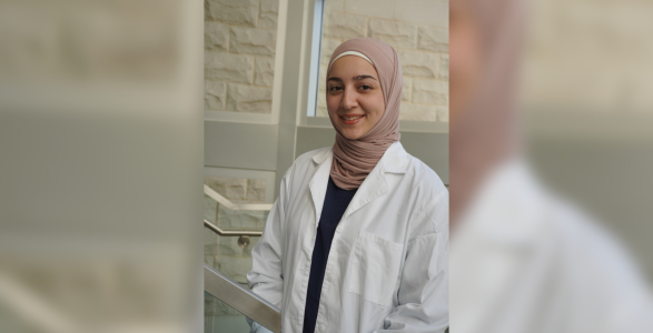 Areej Alfeen headshot in lab coat in the life sciences building