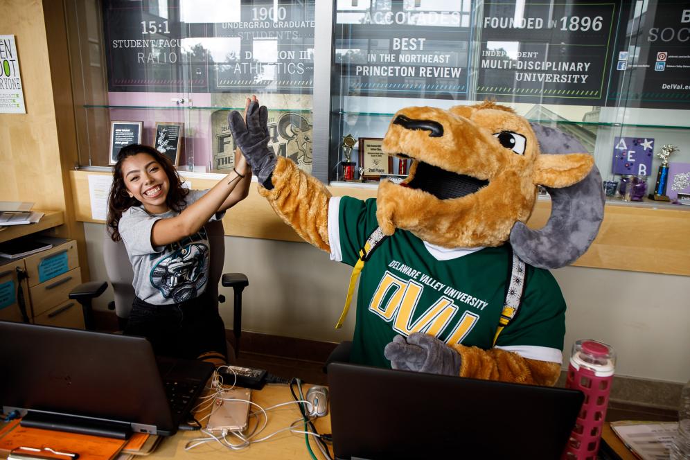 Mascot giving a high five to sitting student.
