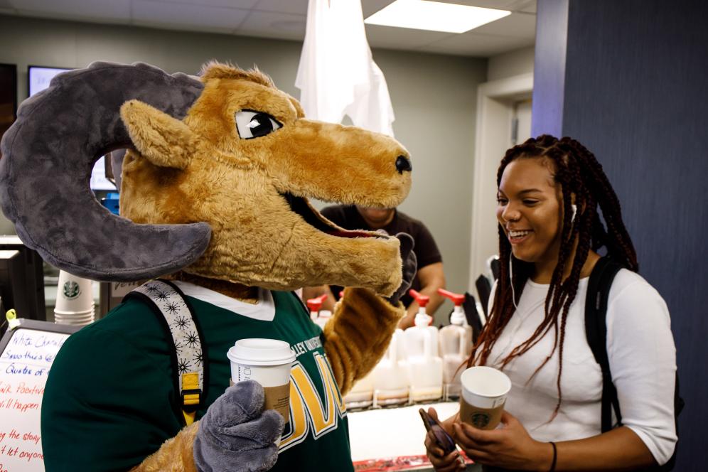 A student and the mascot grab a drink from Starbucks.