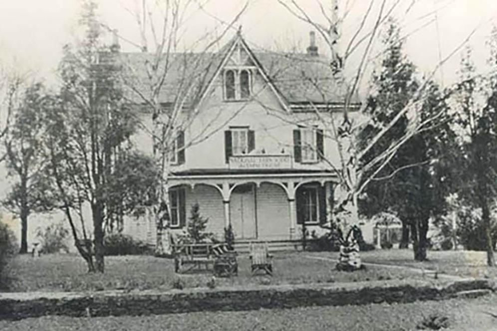 Photo of an old white wood building.