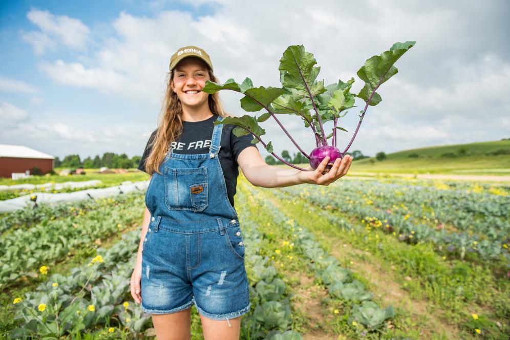 female student holding vegetables in the fields