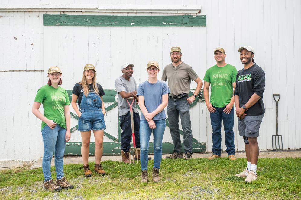 group of students posing outside of a barn