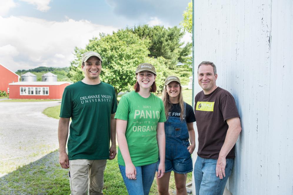 group of students and staff posing outside of a barn