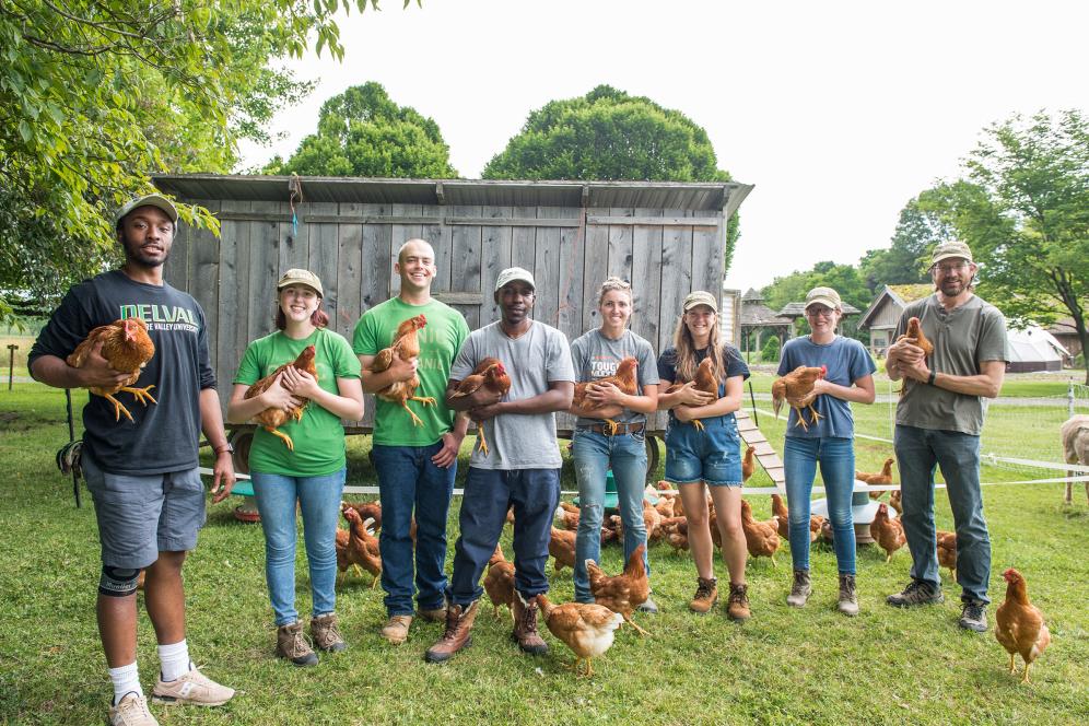 group of students holding chickens in front of a coup