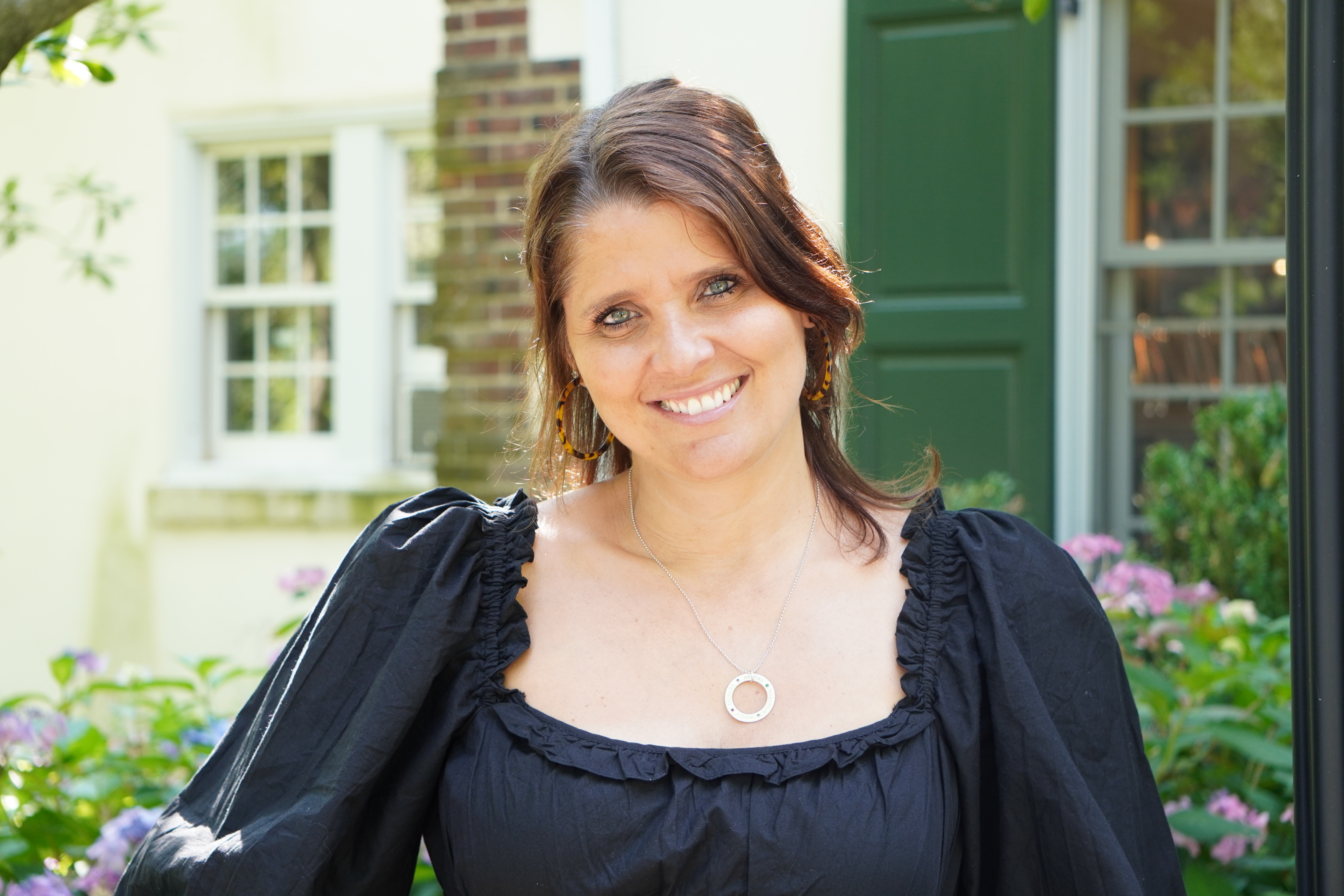 A headshot of Melanie Spratt in front of the admission cottage.