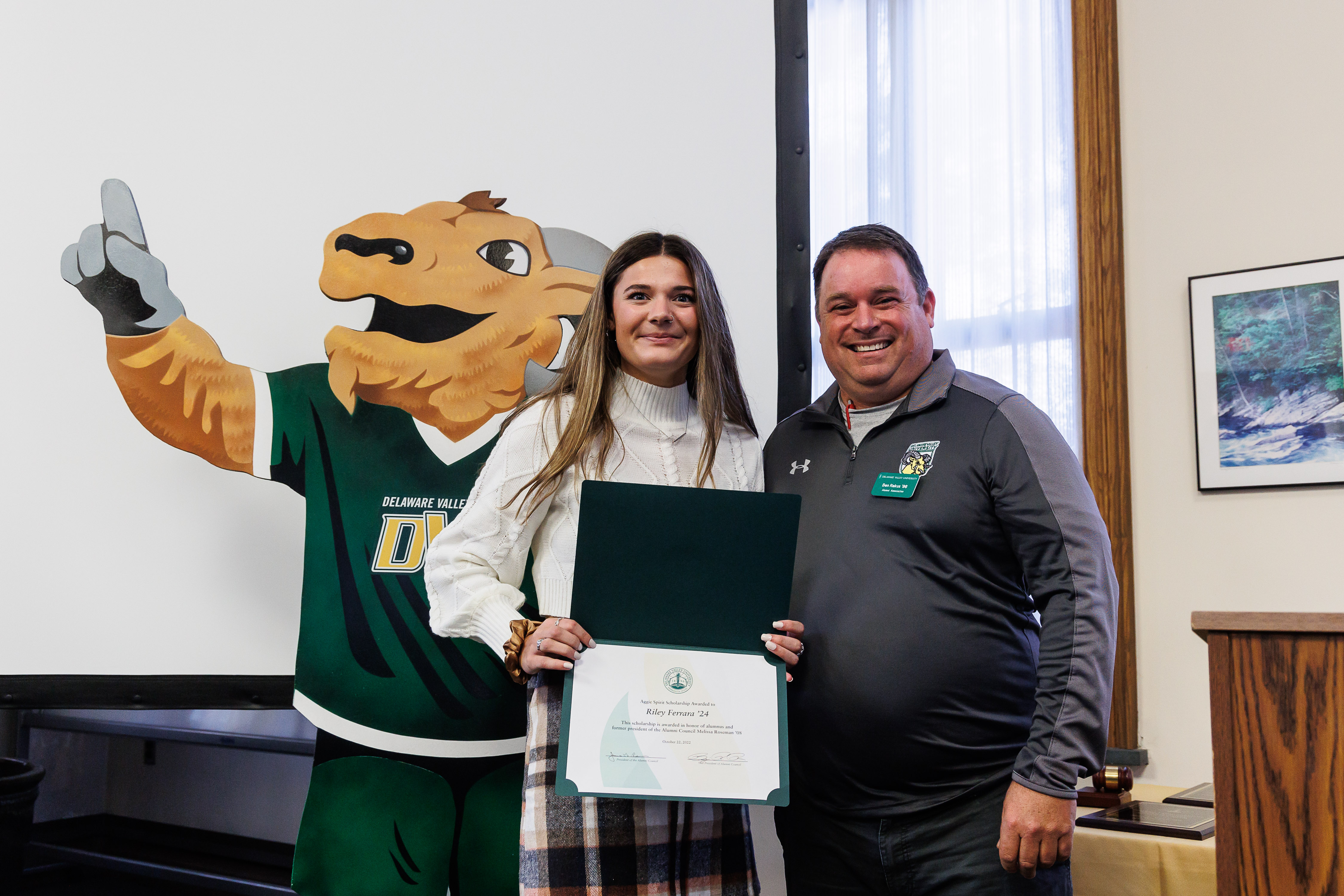 A scholarship recipient is holding a certificate of the achievement.