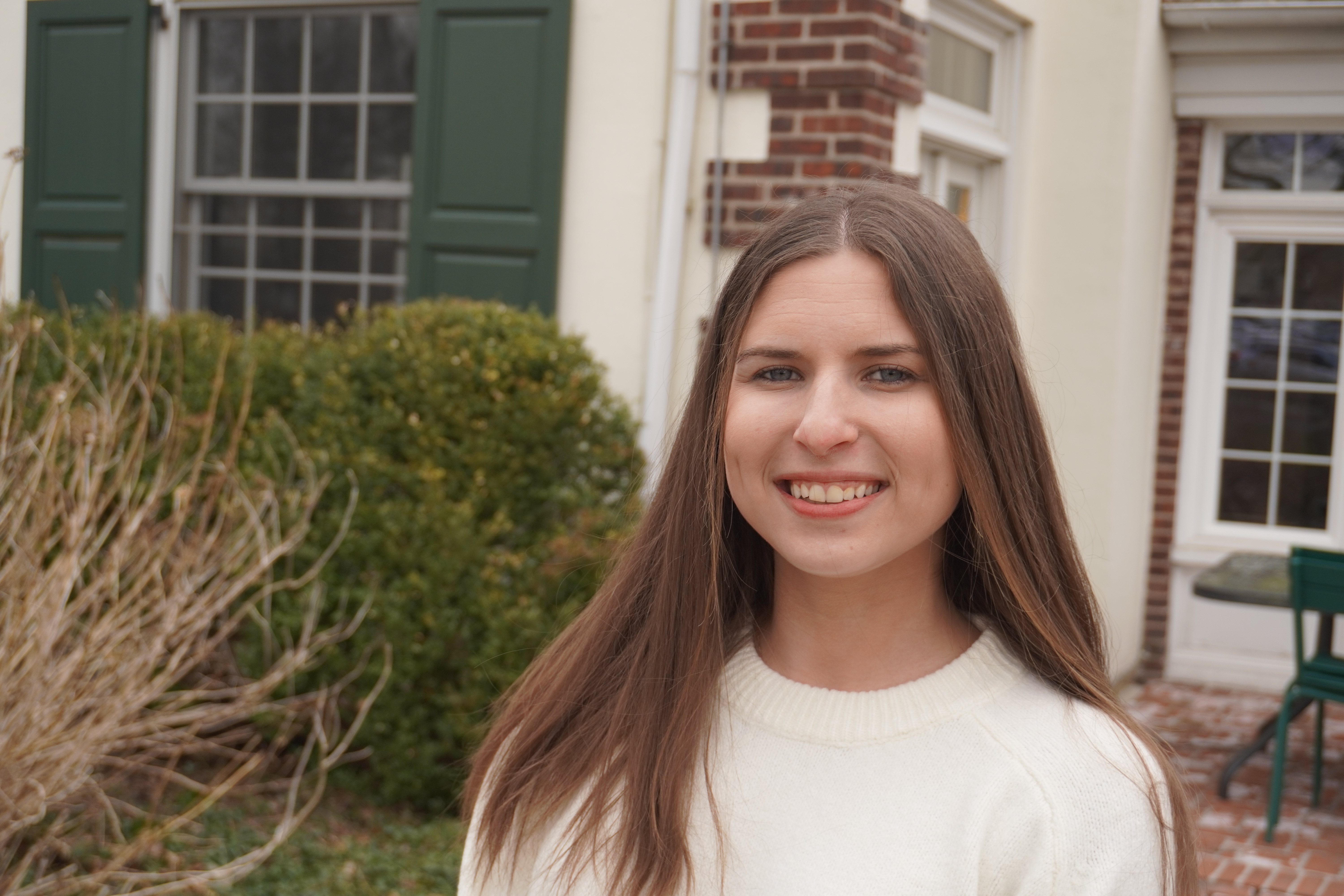Jessica Ellick outside of the admission cottage smiling at the camera for a headshot. 
