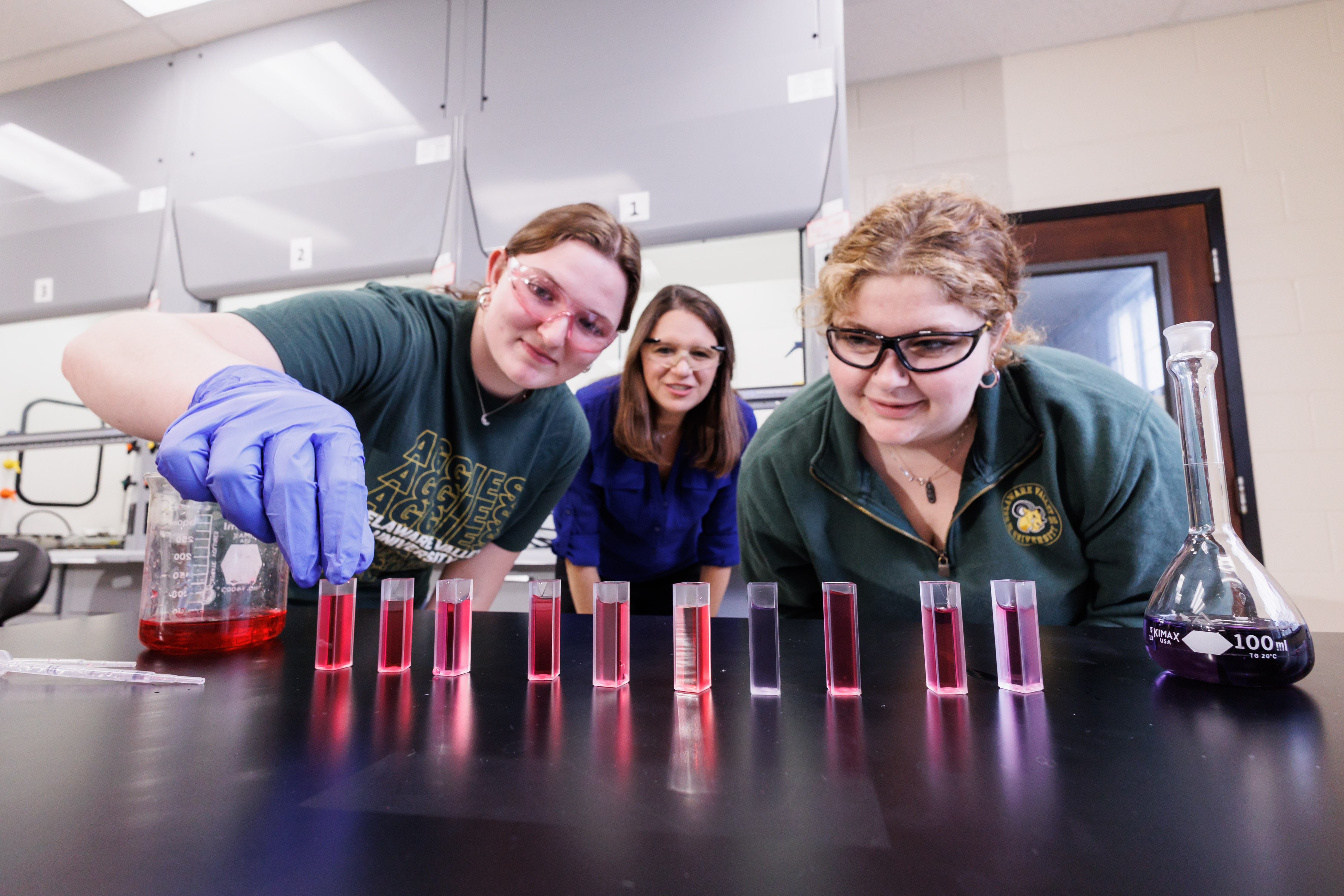 Two students and a professor working with beakers.