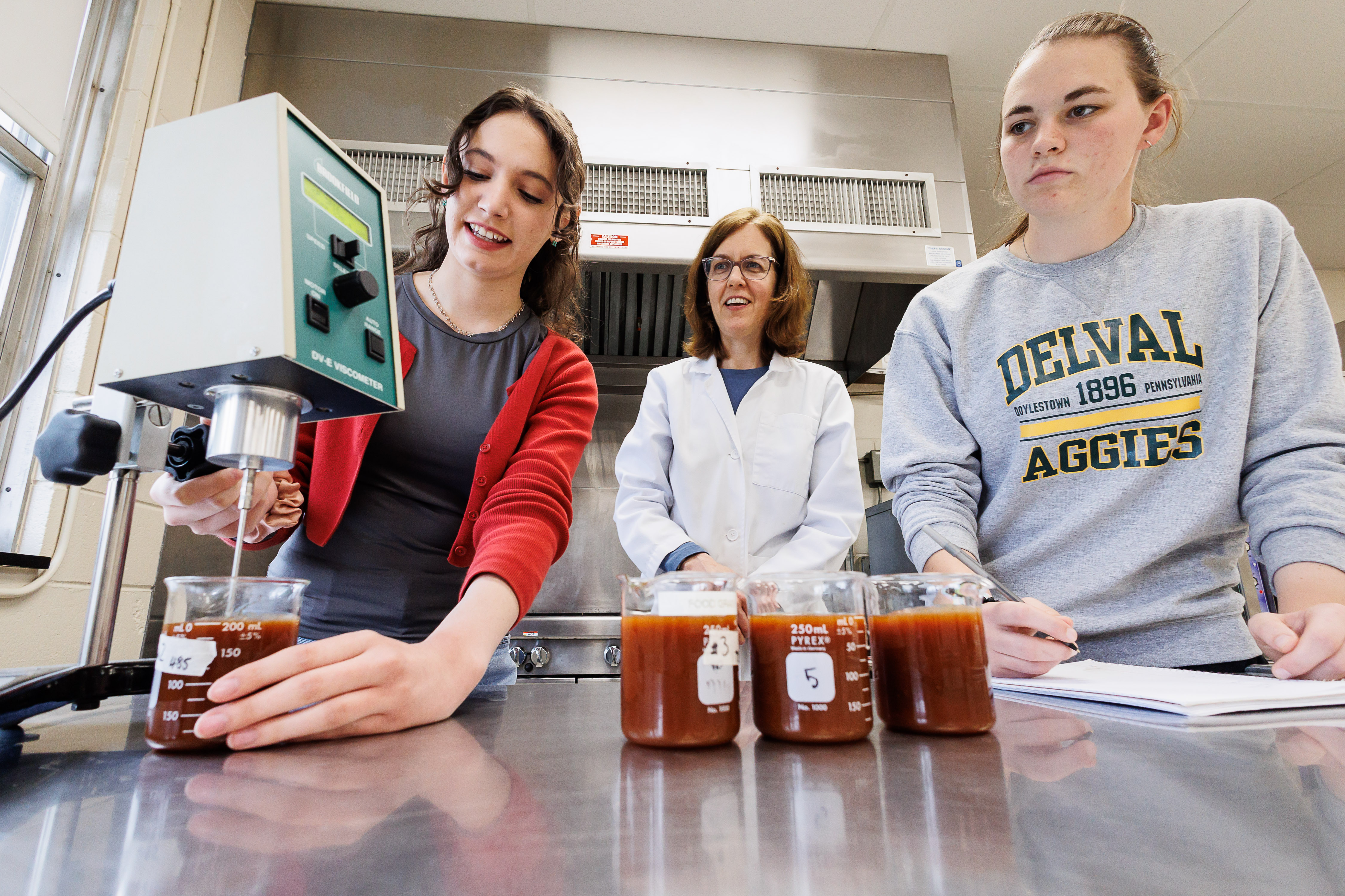 Julia, a food science student, using food science technology to measure liquid in a beaker.