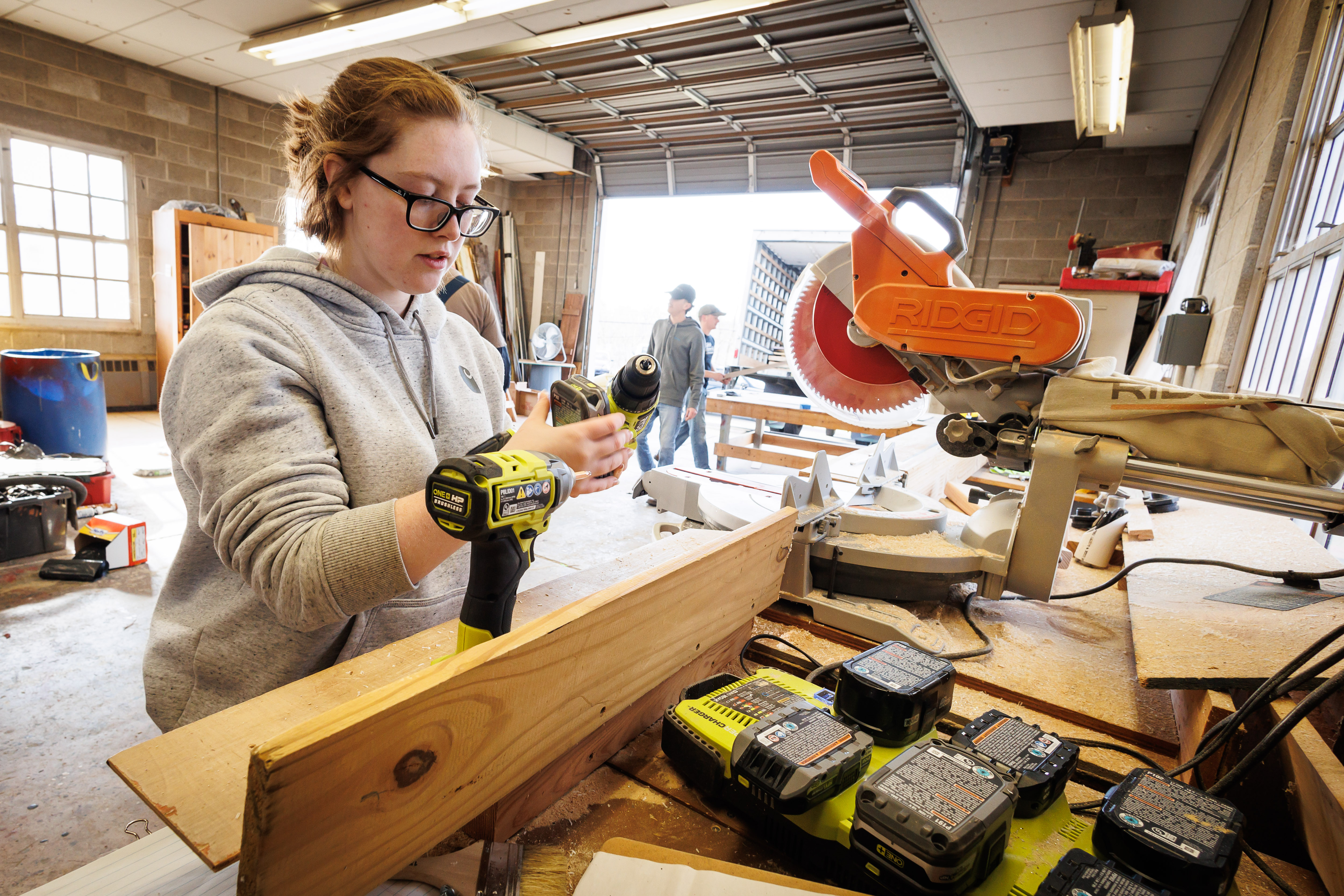 A female student is working on a structure using tools in the landscape design build studio.