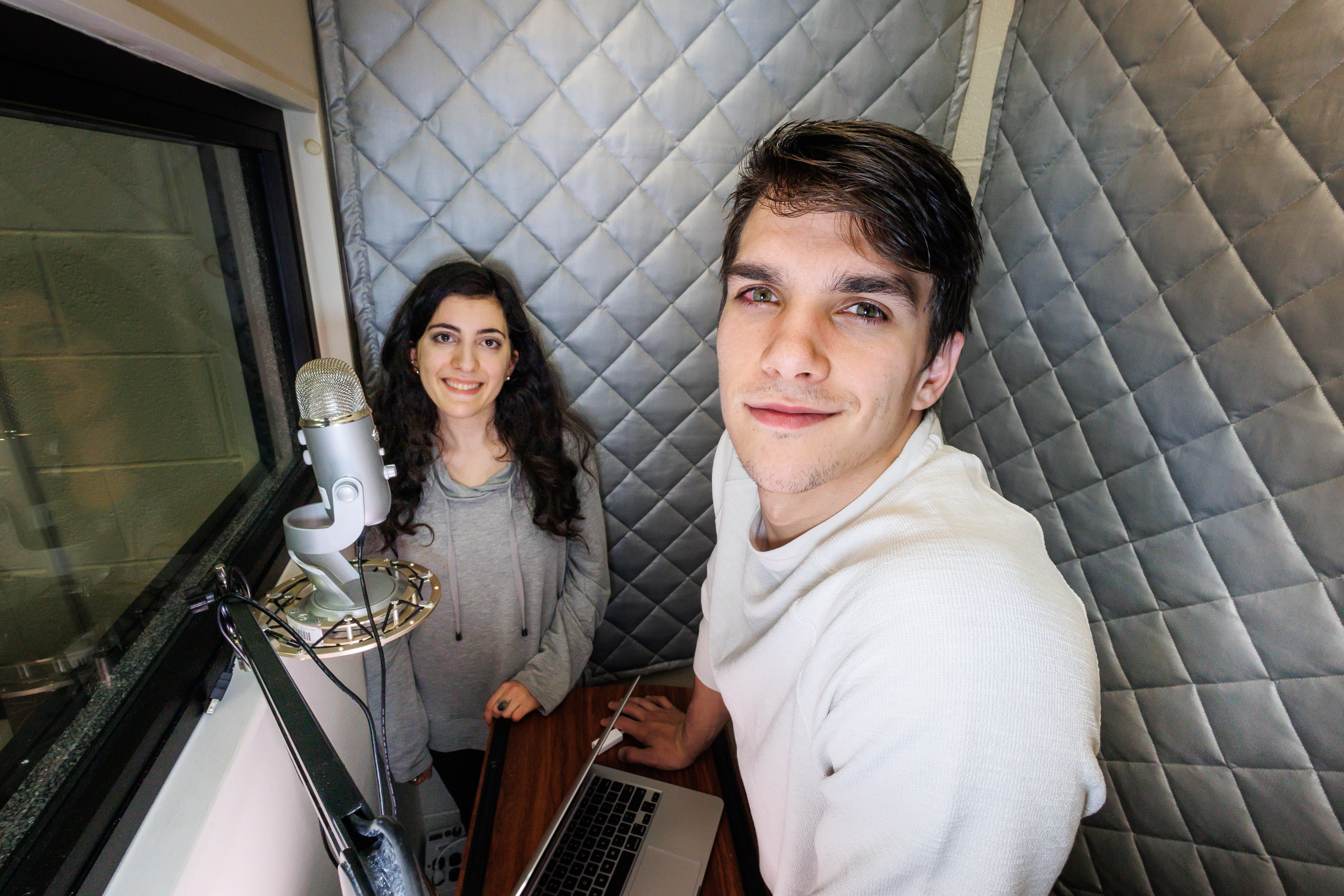 Media and Communication students in the sound booth by a microphone. 