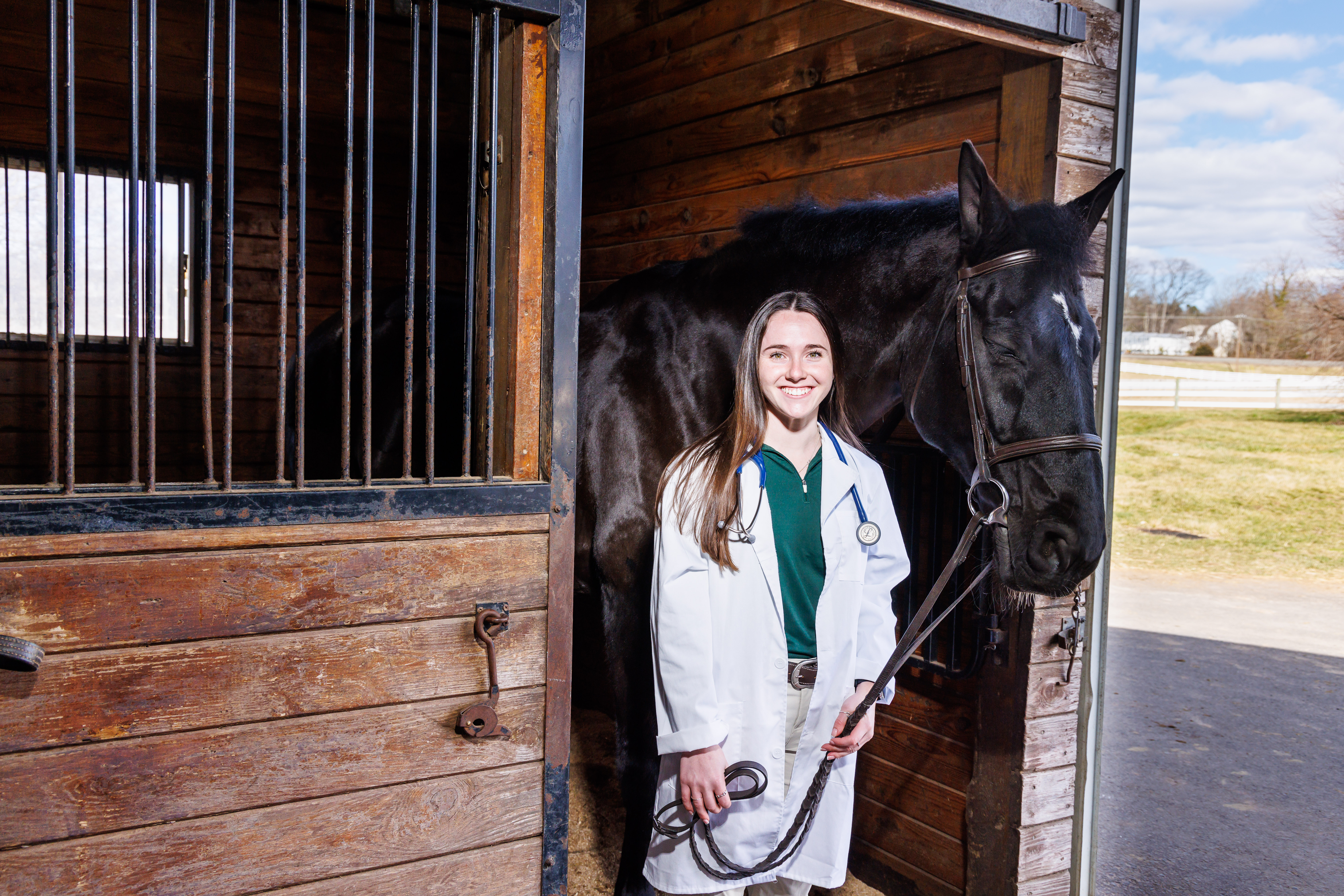 Nina Dellarte wearing a lab coat and horse beside her.