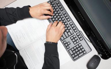 male student's hands typing on a keyboard