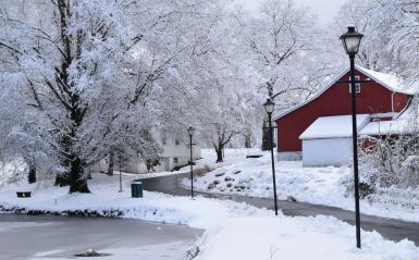 A snowy campus walkway with a red barn.