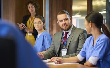 a group meeting at a table with nurses