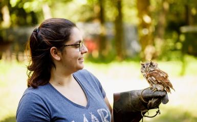 A student at AARK Wildlife Rehabilitation is holding an owl. 