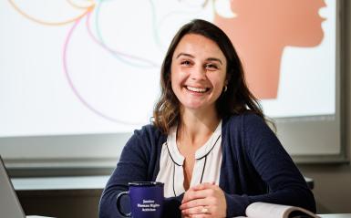 Headshot of Megan Demarest in front of a projector screen in class