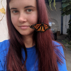 Arianna Logan poses outdoors with a butterfly