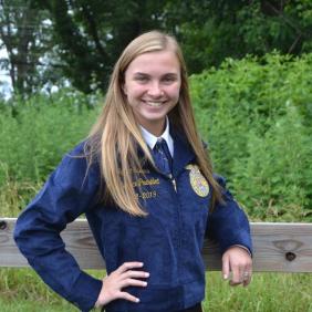 Jamie Specca stands outside in a field in her Future Farmers of America (FFA) jacket