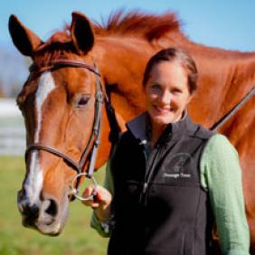 Chair of the Department of Equine Science and Management at Delaware Valley University Cory Kieschnick stands next to a horse.