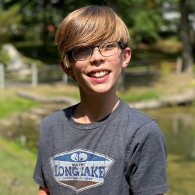 A boy holds a frog by Lake Archer