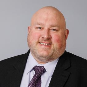 A headshot of Broc Sandelin in a suit and tie.