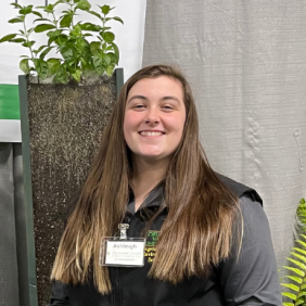 A headshot of Ashleigh Moss at the farm show event standing in front of plants. 