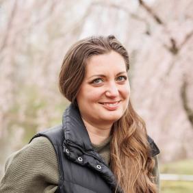A headshot photo of Kimberly Reichner at lake archer wearing a black vest with an olive green long sleeve shirt underneath.