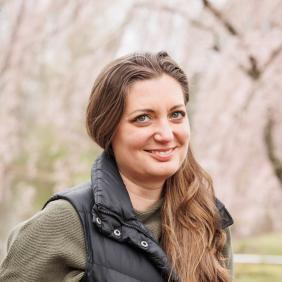 A headshot photo of Kimberly Reichner at lake archer wearing a black vest with an olive green long sleeve shirt underneath. 