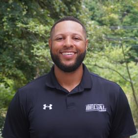 A headshot of Matthew Owens in front of the admissions cottage.