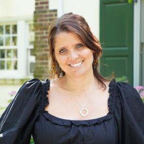 A headshot of Melanie Spratt in front of the admission cottage.