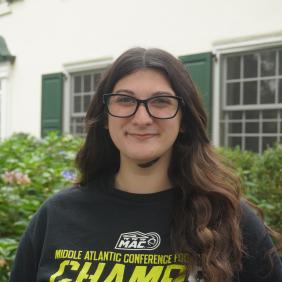 A photo of Stephanie Trimarchi in front of the admissions cottage.