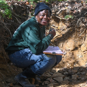 Headshot of Adrianna Lewis in a soil pit doing course work. 