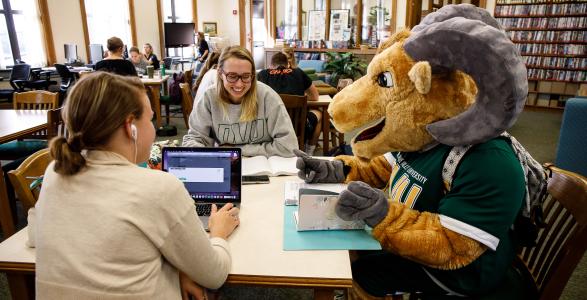Caesar is studying with students in the library 