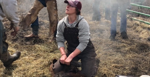 Chrissy Lambert holding an animal in Montana fields alongside coworkers. 