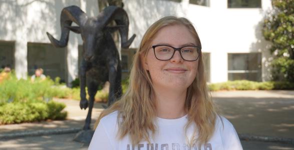 A headshot of Jennifer Giberson, with blonde hair and glasses, infront of the caesar statue at the student center.