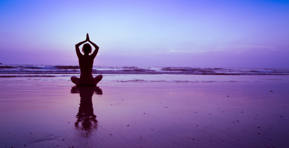 A person meditating by the ocean. 