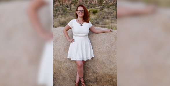 A full body shot of Elizabeth Swift posing in a white dress. 