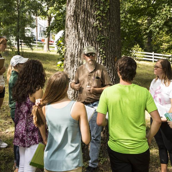 Dr. Bortnick outdoors with a group of students discussing tree growth