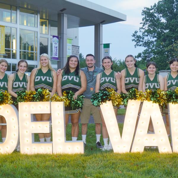 cheer team with a lit up delval sign