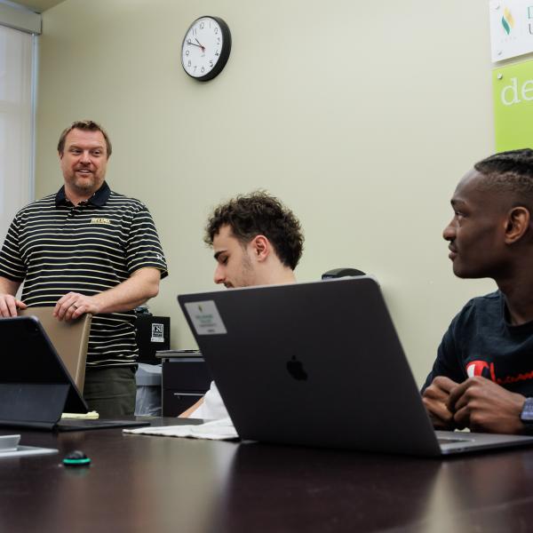 Jeff Wehrung in a conference room with students who are talking with him. 