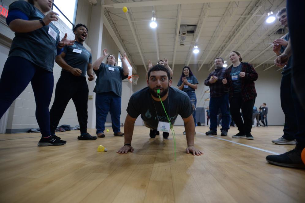 a student making a silly face while doing a push up and blowing a whistle