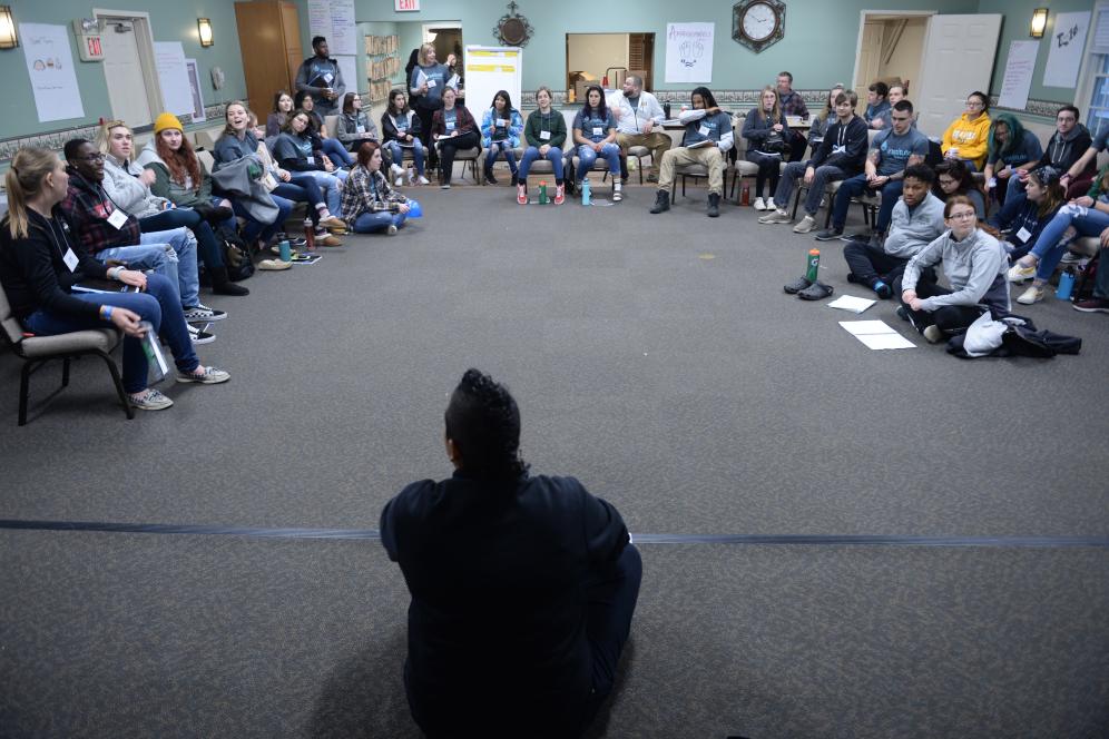 a group sits around the room while listening to the leader.