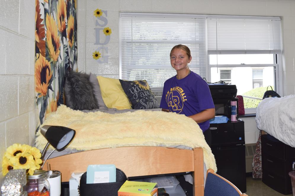 A student stands in her residence hall room at Delaware Valley University next to a MicroFridge. 