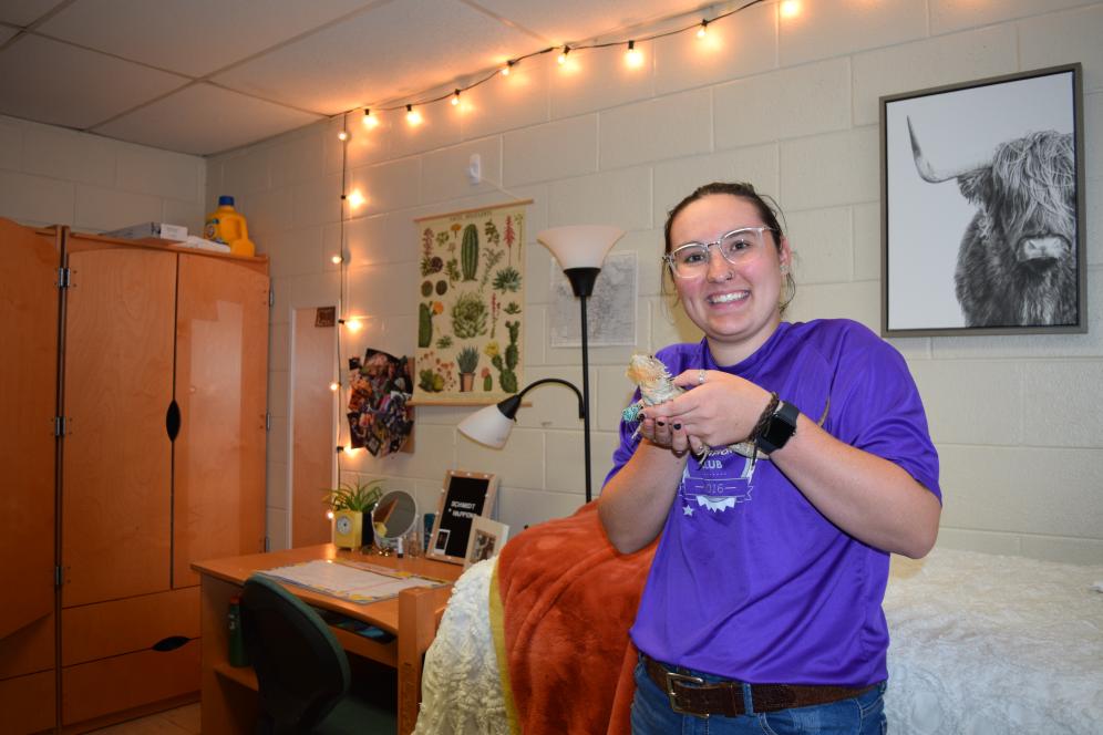 A girl holding her pet in her dorm.