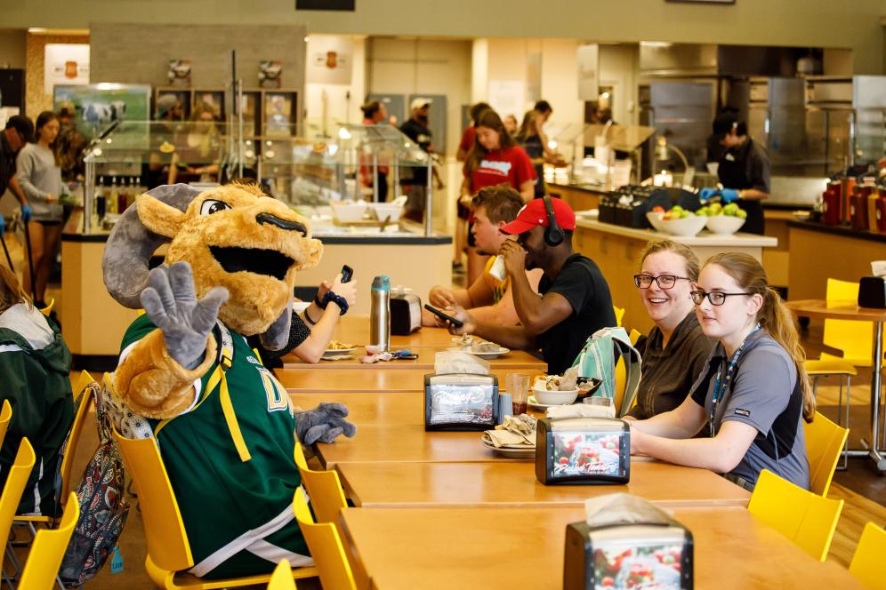 The mascot waving while in the dining hall.