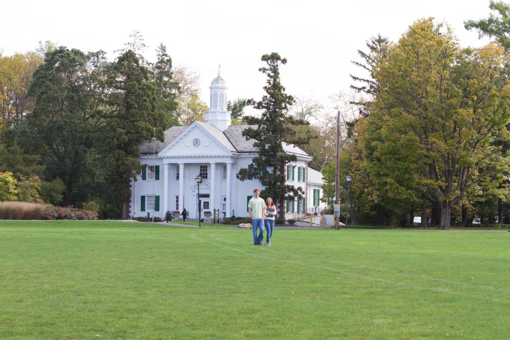 Two students walking across lawn in front of campus building