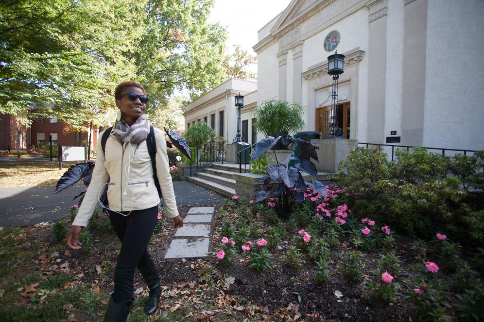 Student walks by beautiful campus building