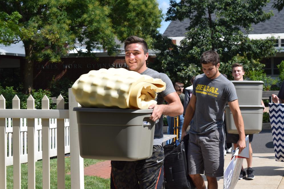 Two students carry boxes of belongings into a residence hall at Delaware Valley University on Move-In Day.