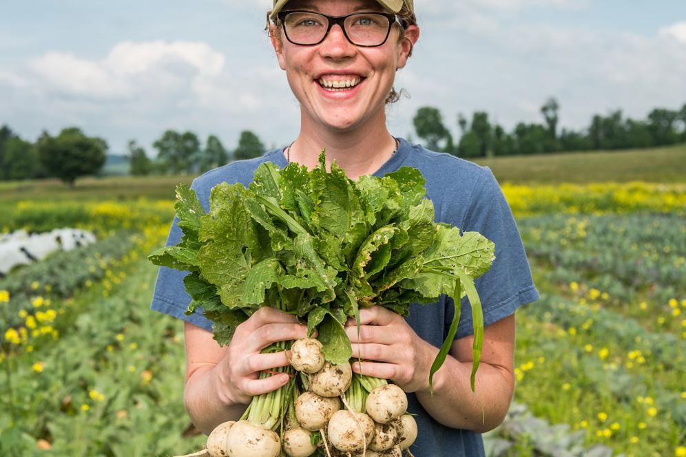 female student holding vegetables in the fields